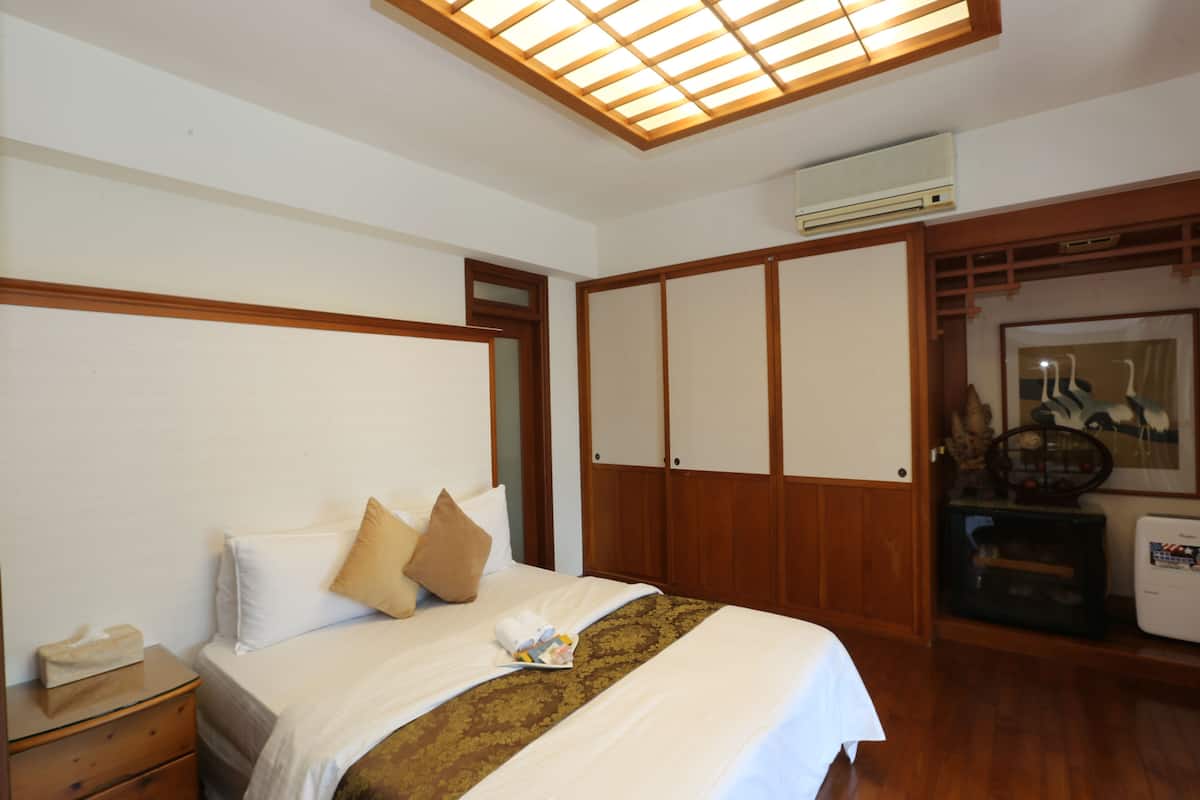 A hotel room with a bed, wooden wardrobe, and a ceiling fan.
