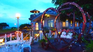 A house with a balcony, outdoor seating, and decorative elements like a heart-shaped swing and bear figures. - Memory Garden Villa (Luodong)
