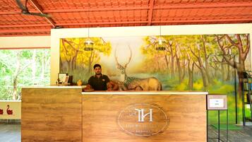 Mostrador de recepción en un resort con un mural de un ciervo y árboles, un logotipo y un cartel para propinas.