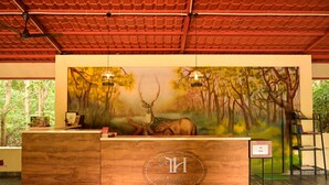 A reception desk with a wooden finish, a mural of a deer in a forest, and a sign reading "TIGERS' HEAVEN RESORT". - Tigers Heaven Resort (Chimur)