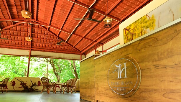 A reception area with a wooden desk, wicker chairs, and a ceiling fan. - Tigers Heaven Resort (Chimur)