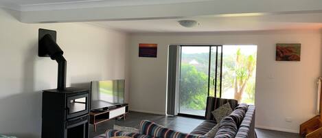 A living room with a sofa, a TV, a fireplace, and a view through a sliding glass door.
