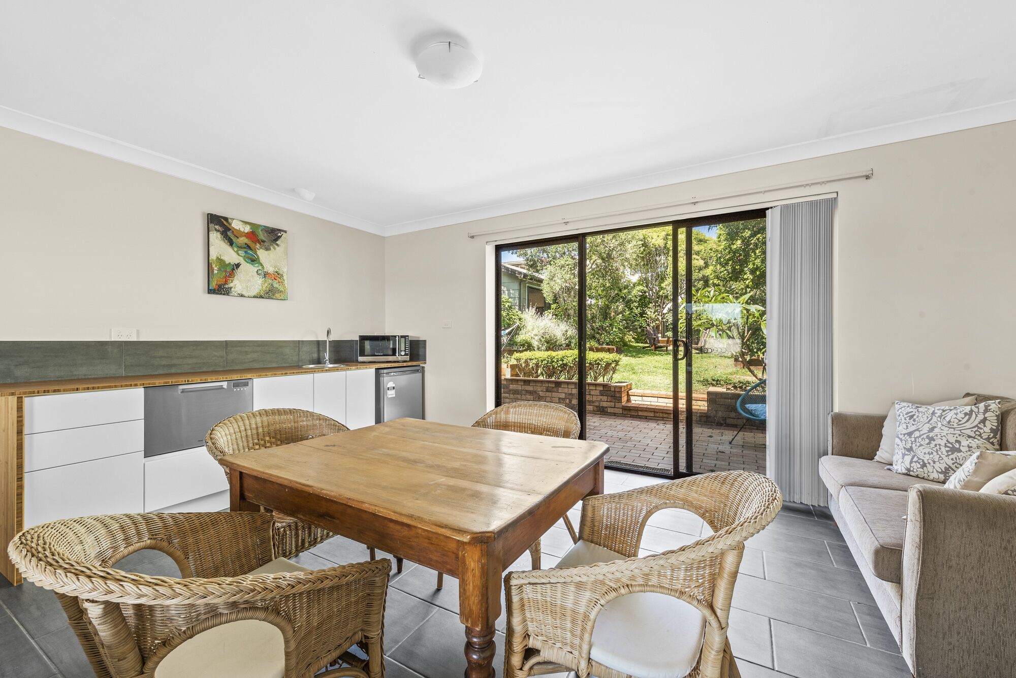 Una cocina moderna con comedor, sofá y vistas al jardín.
