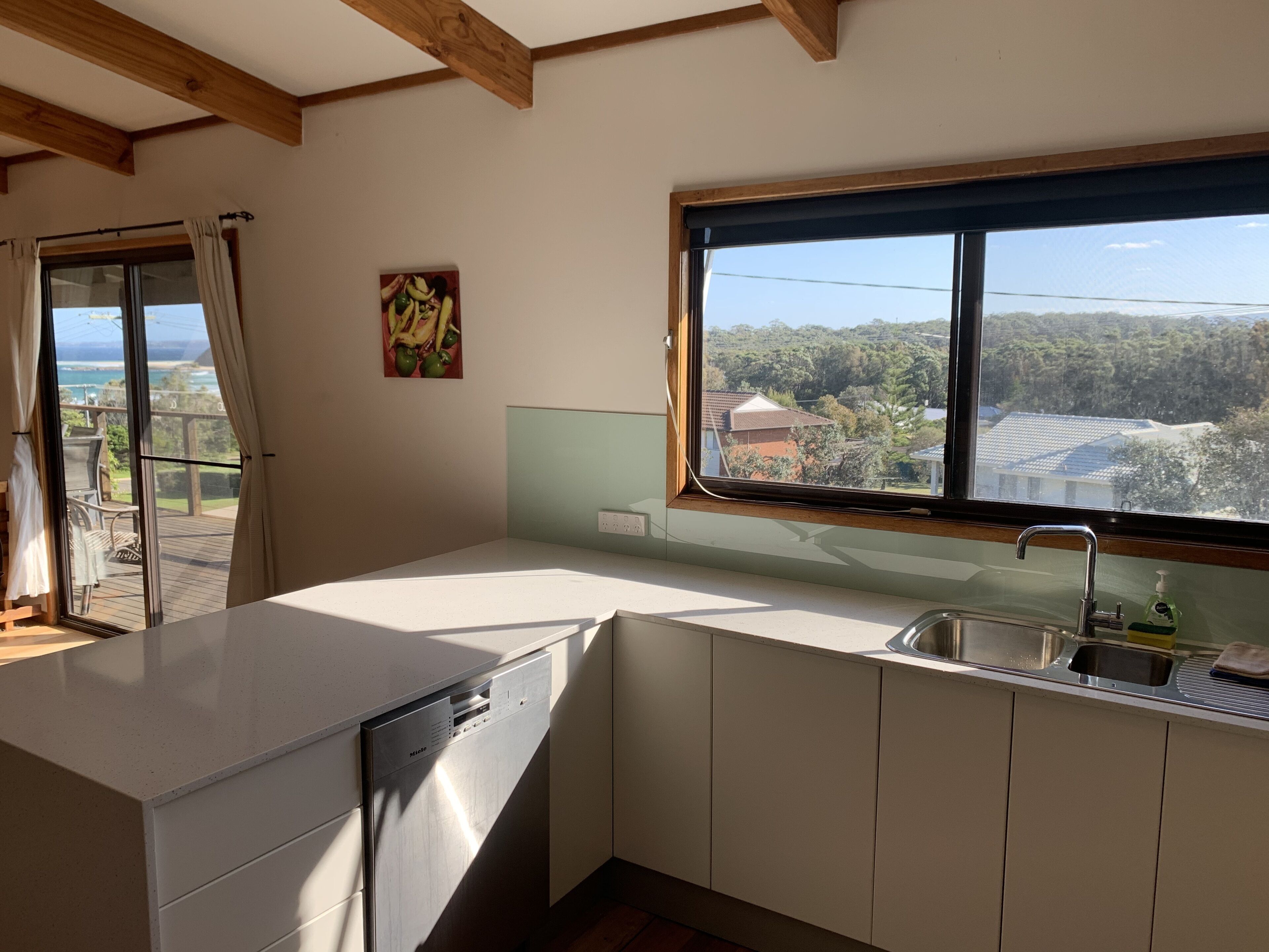 A modern kitchen with a dishwasher, a sink, and a window offering a view of a residential area.
