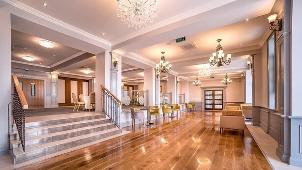 A spacious lobby with a polished wooden floor, a staircase, and multiple seating areas. - Frontier Europe Hotels Group (Siret)