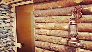 A wooden door with a stone wall and a metal lantern on a log wall. - Frontier Europe Hotels Group (Siret)