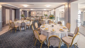 A spacious banquet hall with round tables, gold chairs, and floral centerpieces. - Frontier Europe Hotels Group (Siret)