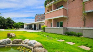 A modern building with a well-maintained lawn, a small pond, and a stone pathway. - Dong Pan B&B (Shoufeng)