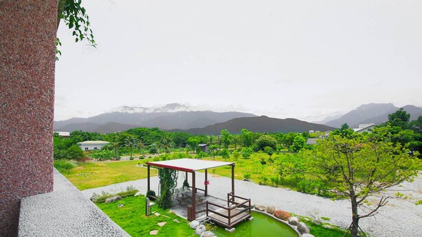 A serene garden with a wooden gazebo, a small pond, and a view of distant mountains. - Dong Pan B&B (Shoufeng)