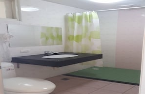 A bathroom with a white toilet, a black sink with a mirror above it, and a shower area with a green mat. - Dong Pan B&B (Shoufeng)