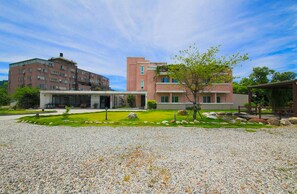 A building with a modern design, featuring a large entrance and a well-maintained garden area with a small tree and rocks. - Dong Pan B&B (Shoufeng)