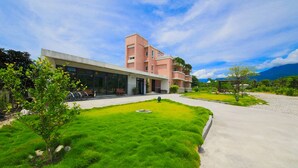 A modern building with a flat roof, a paved driveway, and a well-maintained lawn with a small tree and a spherical sculpture. - Dong Pan B&B (Shoufeng)