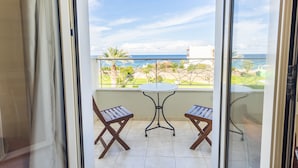 A balcony with a table and two chairs, overlooking a garden and the sea. - Pela Sofia (Hersonissos)