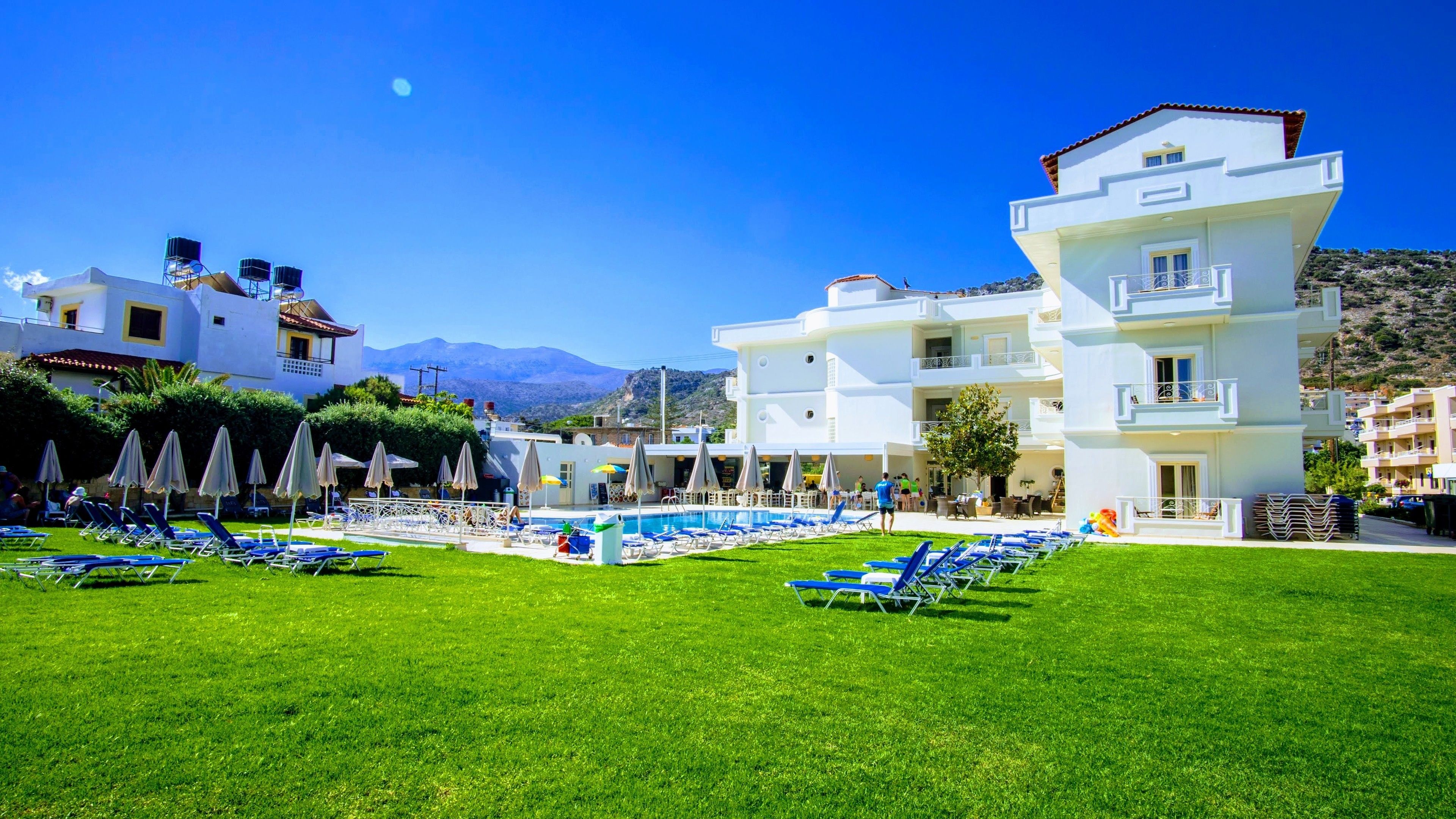 A hotel with a pool area, multiple lounge chairs, and a mountainous backdrop.