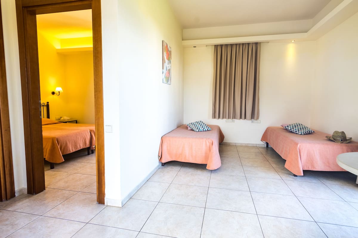 Una habitación de hotel con dos camas, un baño y una ventana con cortinas.