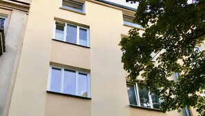 Un immeuble à plusieurs étages, doté d’une façade beige, de nombreuses fenêtres à encadrements blancs et d’une enseigne indiquant qu’il s’agit d’un immeuble d’habitation.