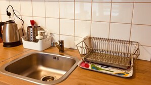 Une cuisine équipée d’un évier en acier inoxydable, d’une bouilloire, d’un égouttoir et d’un porte-ustensiles.