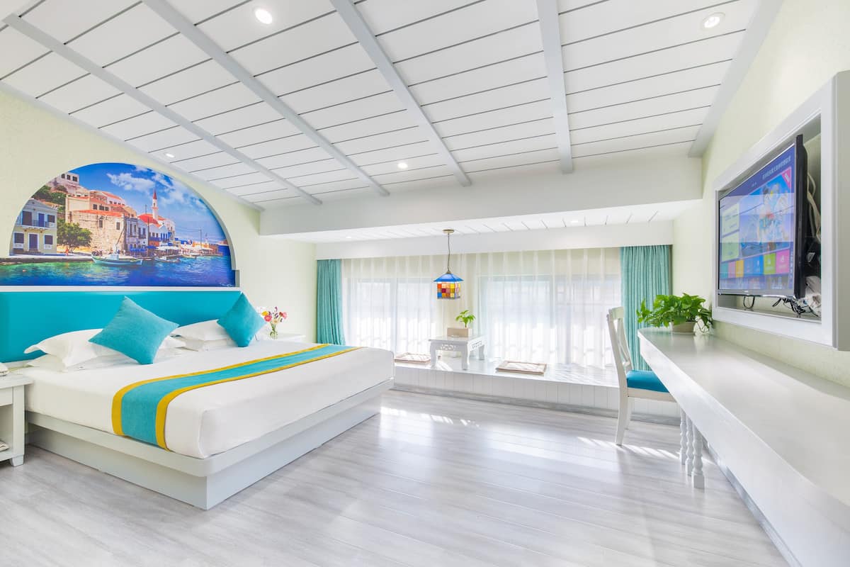 A modern hotel room with a large bed, a desk, and a TV.