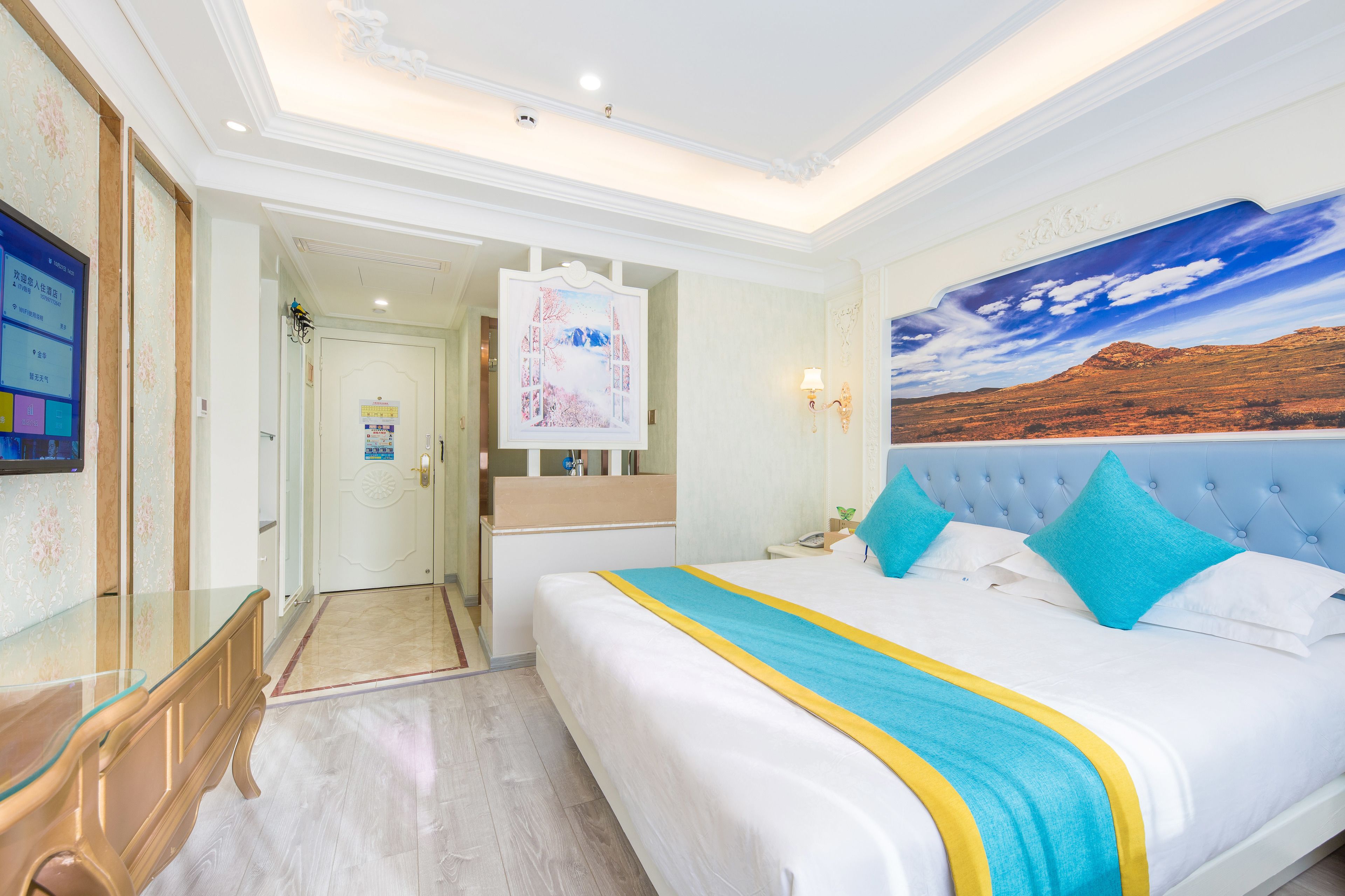 Una habitación de hotel con una cama grande, un cuadro de un paisaje y una mesa de centro de vidrio.