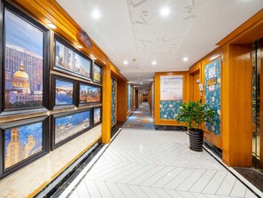 A hotel corridor with framed cityscape pictures on the walls, a patterned carpet, and a potted plant. - YiWu Defeng Hotel (Jinhua)