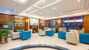 A hotel lobby with a reception desk, seating area with sofas, a fireplace, and a view of the street outside. - YiWu Defeng Hotel (Jinhua)