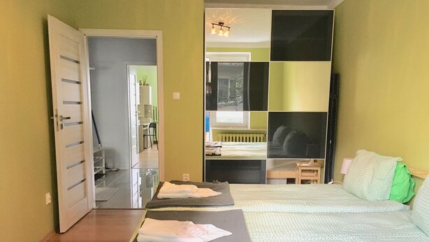 Une chambre à coucher avec un lit, un bureau et une chaise. Une porte donne accès à une autre pièce.