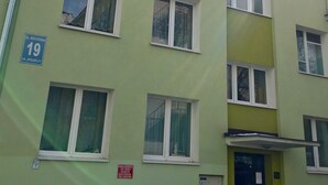 Un immeuble à plusieurs étages, doté de fenêtres numérotées, d’une entrée bien visible et d’une enseigne indiquant un lieu précis.