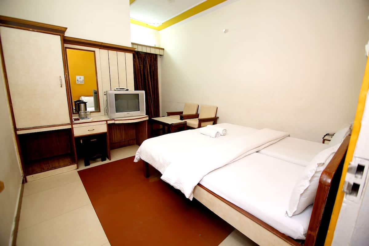 A hotel room with a bed, a desk with a television, a chair, and a wardrobe.