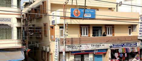 A hotel named 'Hotel Mid Town' with a signboard, a visible entrance, and a street view with shops and vehicles.