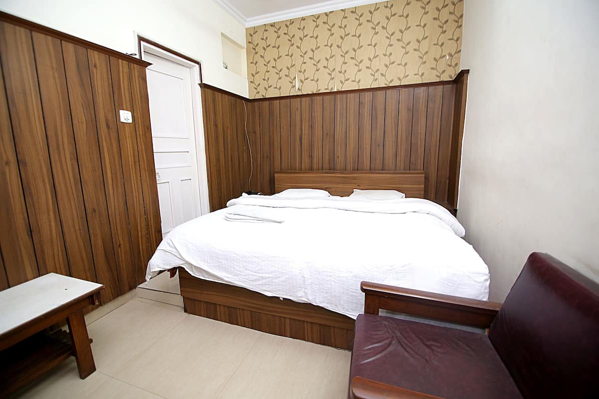 A bedroom with a wooden bed, a wooden bench, and a wooden chair.