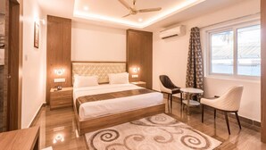 A modern bedroom with a large bed, a desk, a chair, and a ceiling fan. - Grand Paradise (Port Blair)