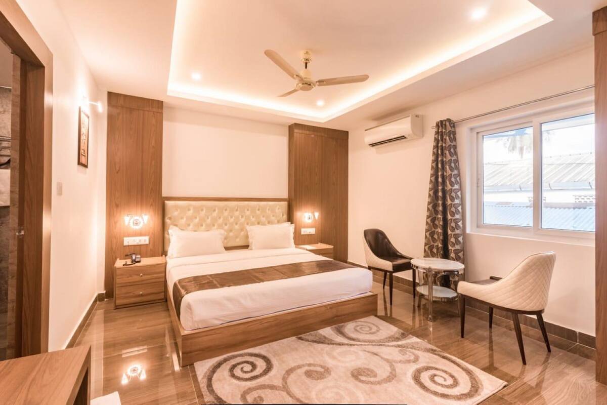 A modern bedroom with a large bed, a desk, a chair, and a ceiling fan.
