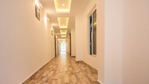 A long, narrow hallway with wooden flooring and recessed lighting. - Grand Paradise (Port Blair)