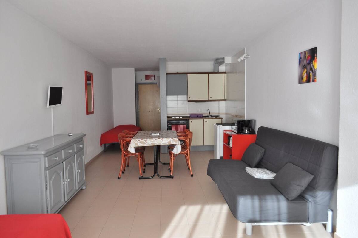 A compact living space with a kitchenette, a dining area, and a sofa.