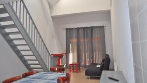 Ein großzügiger Wohnbereich mit Treppe, einer Couch, einem Esstisch und einem Fernseher.