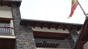 Ein Gebäude mit steinernen und hölzernen Fassade, Balkonen mit Metallgeländern und einer Flagge.