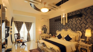 A spacious bedroom with a large bed, a vanity, and a sitting area with a chair and table.