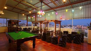 A pool table in a spacious room with a view of the cityscape through large windows.