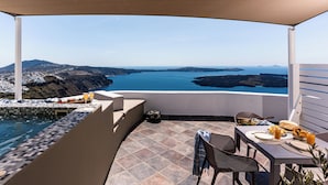 Terraço com piscina, mesa de jantar e cadeiras, com vista panorâmica para a costa e o mar.