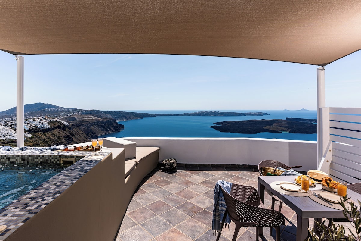 Terraza con piscina, mesa de comedor y sillas con vistas panorámicas de la costa y el agua.