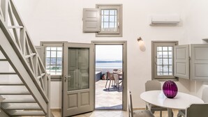 Um quarto com vista para o mar, uma área de refeições com mesa e cadeiras, e uma escadaria.