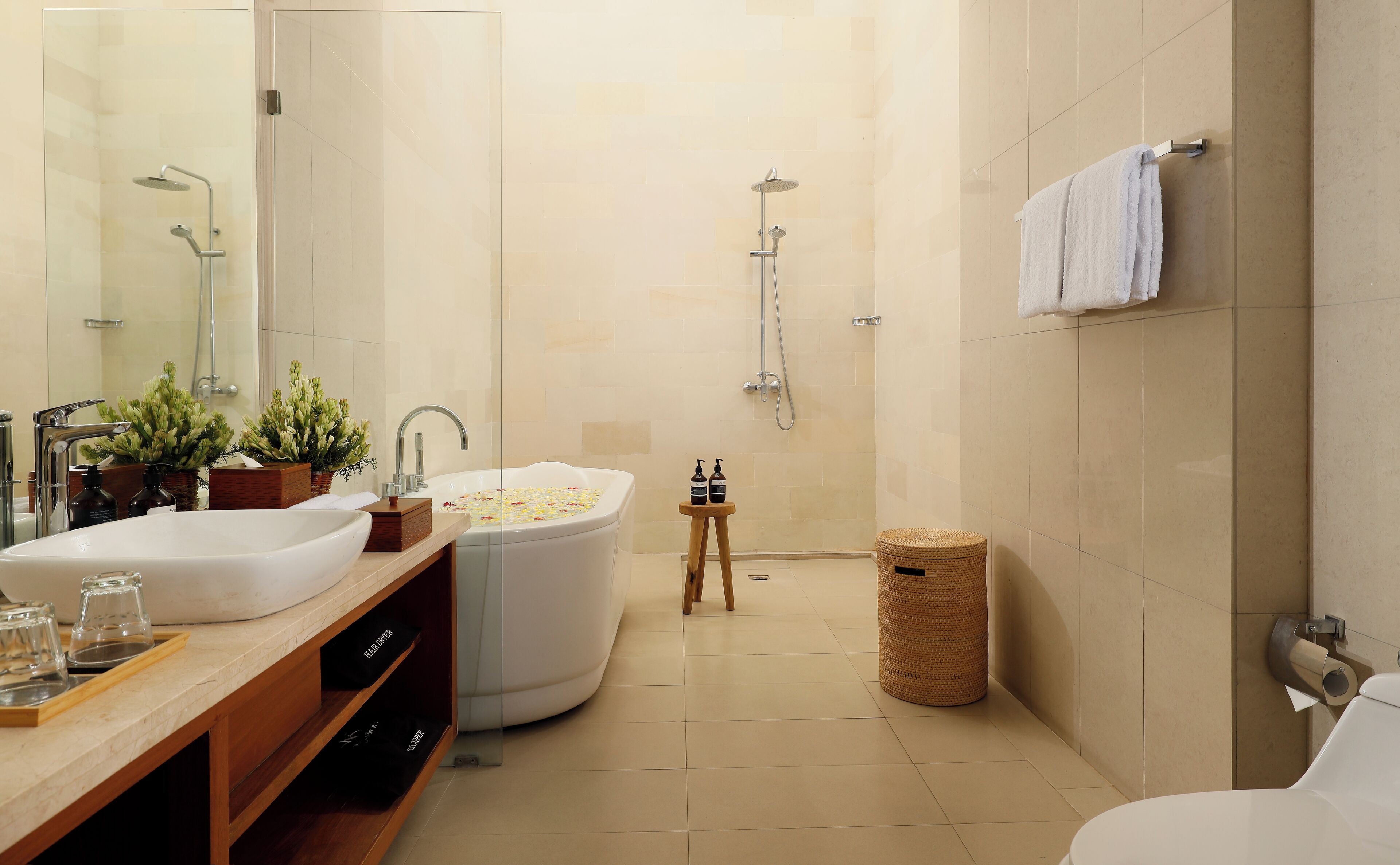 A modern bathroom with a large bathtub, a separate shower area, and a vanity with a sink and mirror.
