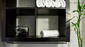 A wall-mounted shelf with a camera, a rolled towel, and a bamboo plant. - Hôtel Mas le Sauvageon (Saintes-Maries-de-la-Mer)