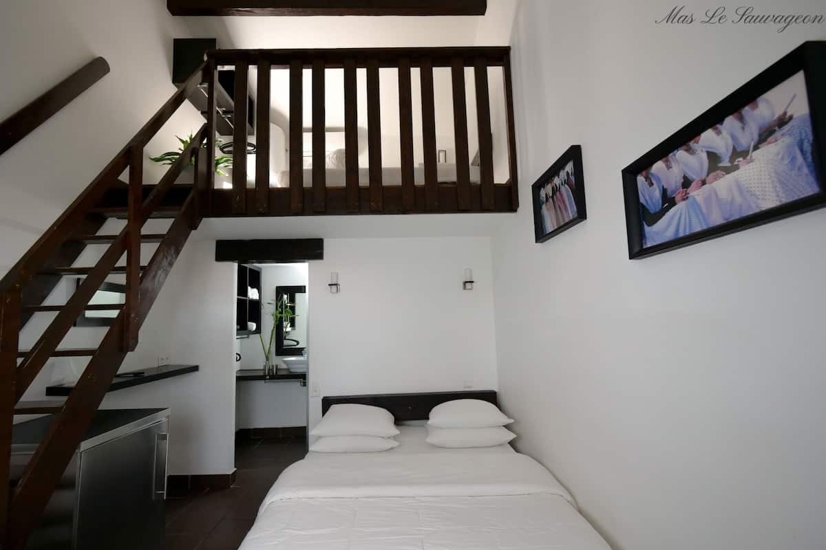 Une chambre à coucher avec un lit, un escalier en bois, une salle de bain et un tableau encadré au mur.