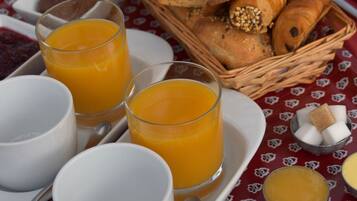 A breakfast setting with orange juice, bread, and sugar cubes on a table.