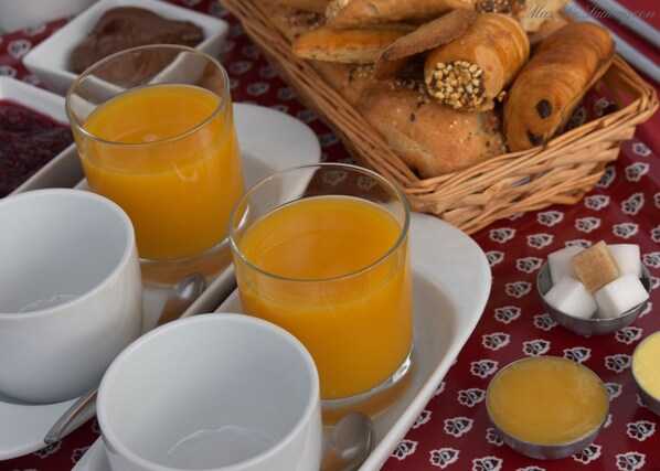 Un desayuno con jugo de naranja, pan y terrones de azúcar sobre una mesa.