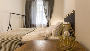 A neatly made bed with white linens, a wooden bedside table, and a yellow lamp. - Visit Lublin Premium Radziszewskiego (Lublin)