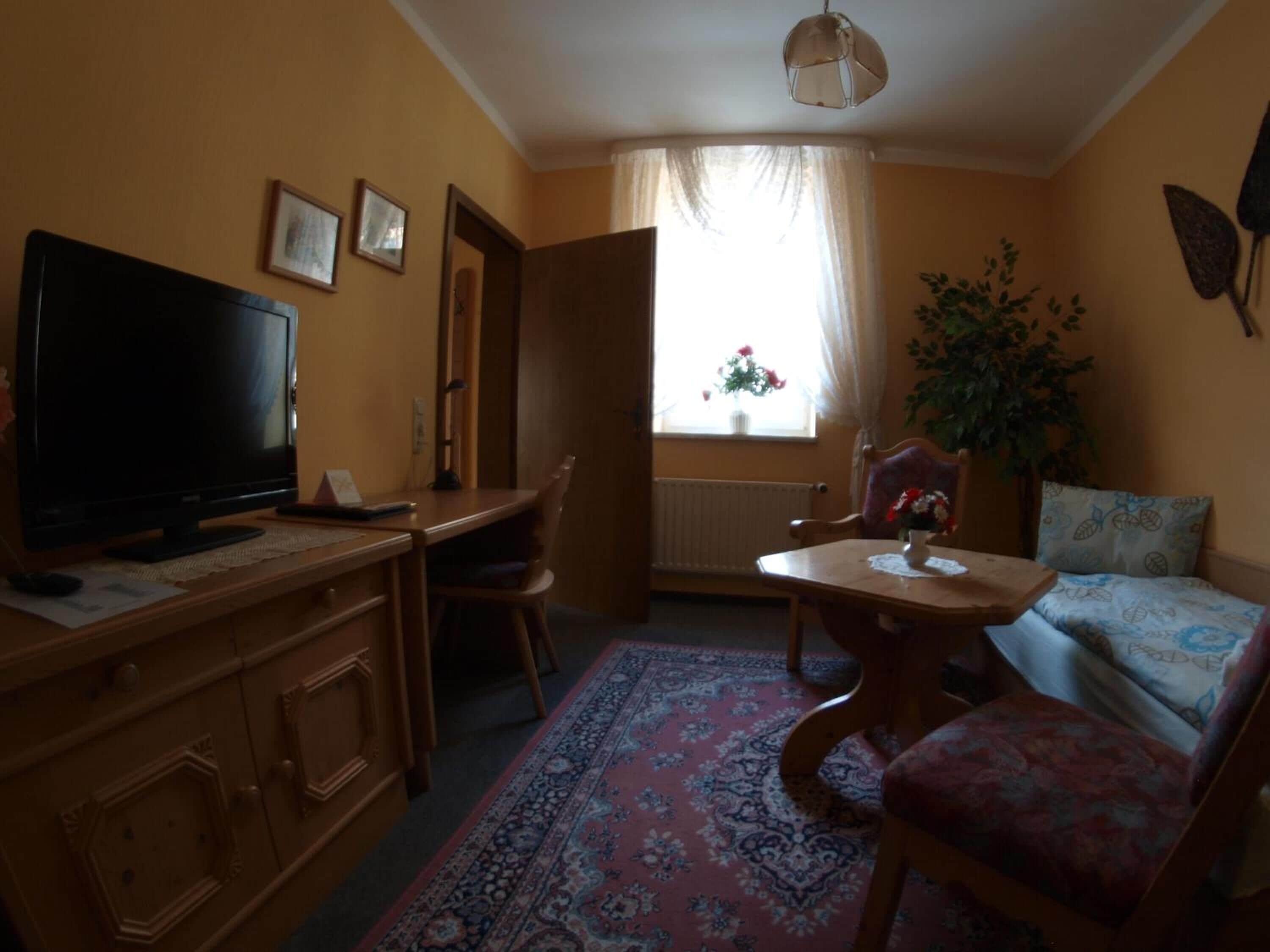 Una sala de estar acogedora con televisor, una mesa de comedor y un sofá.