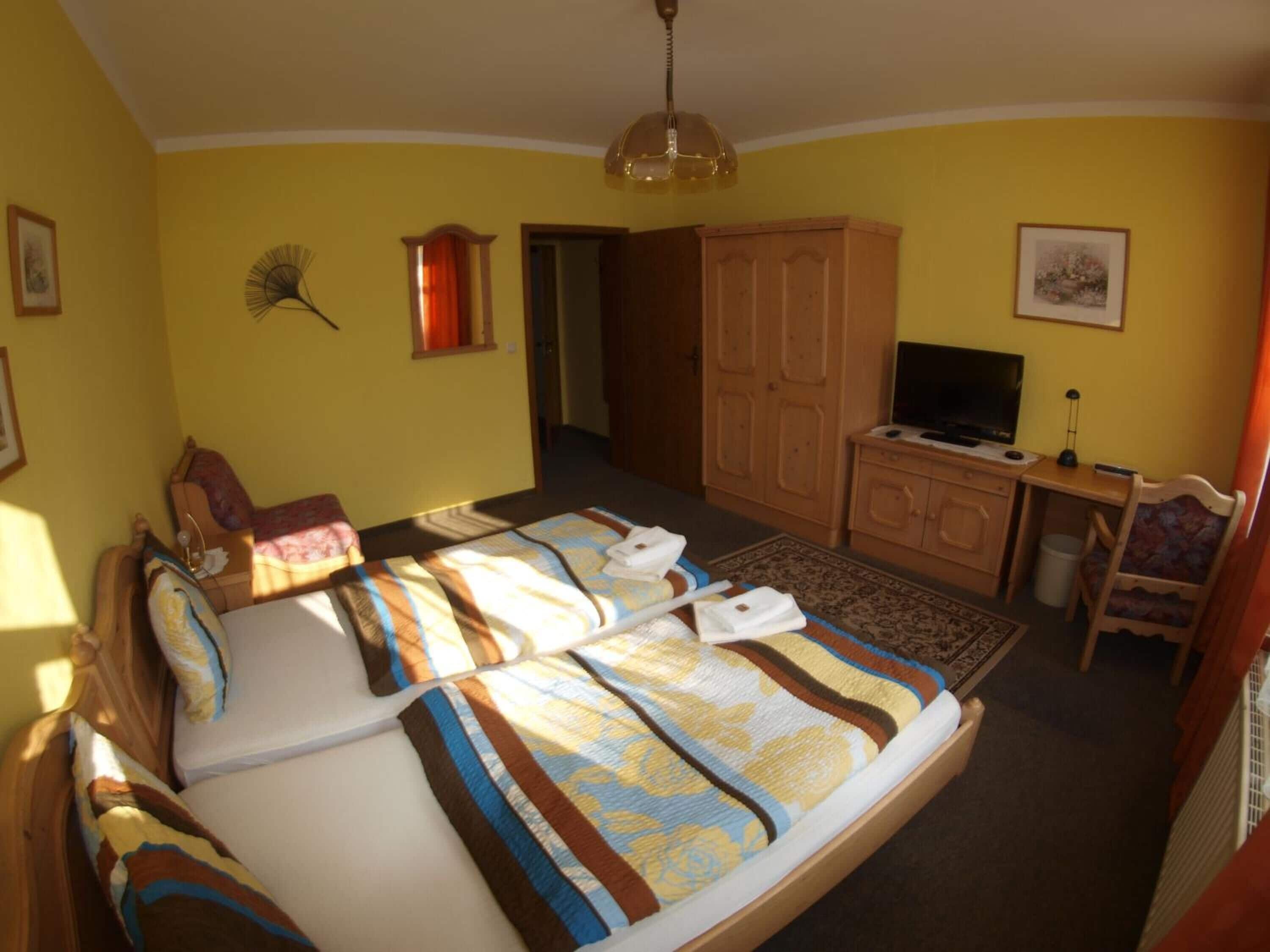 Un dormitorio con cama, escritorio, televisor y armario.