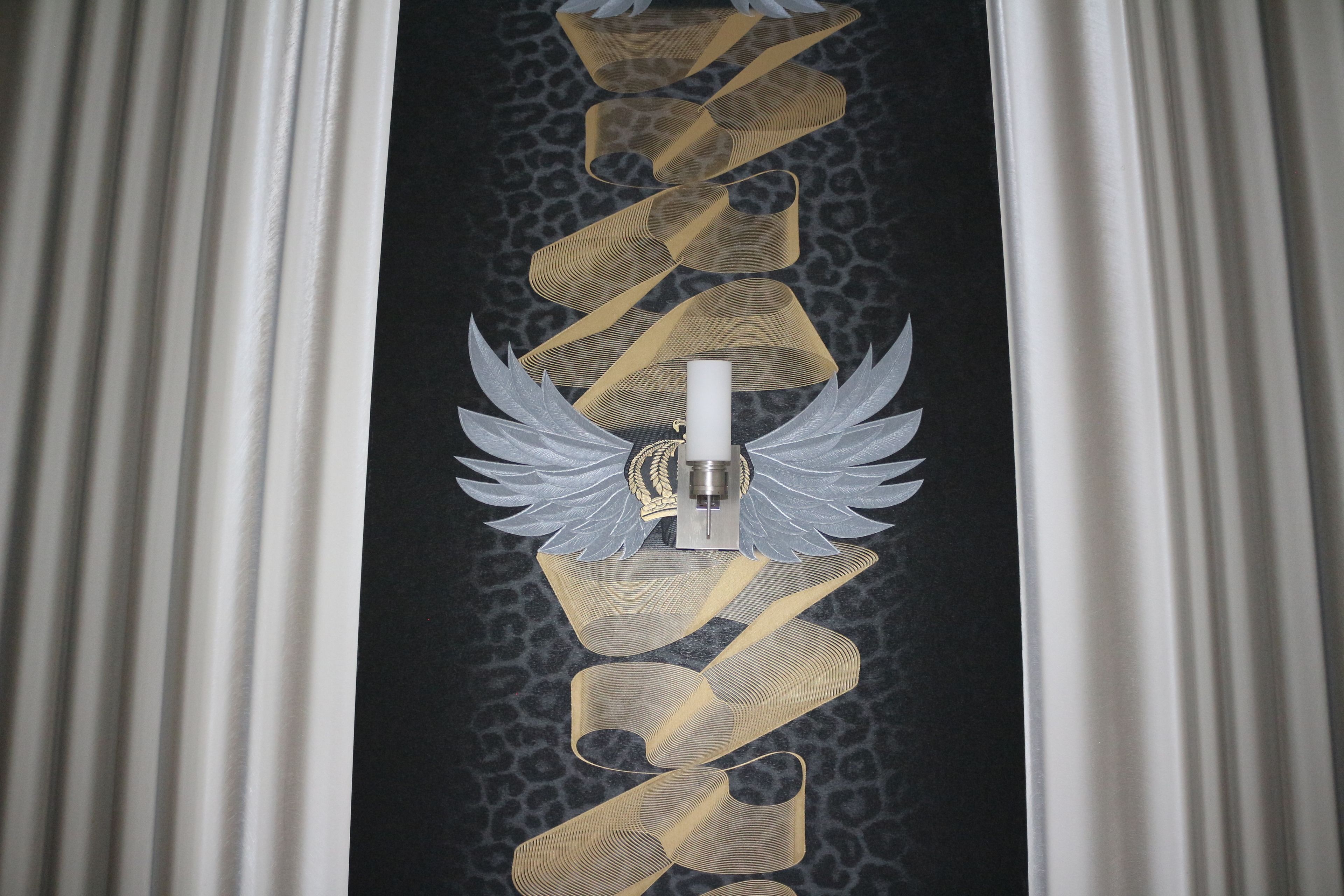 A vertical ribbon design with a central emblem on a dark background.